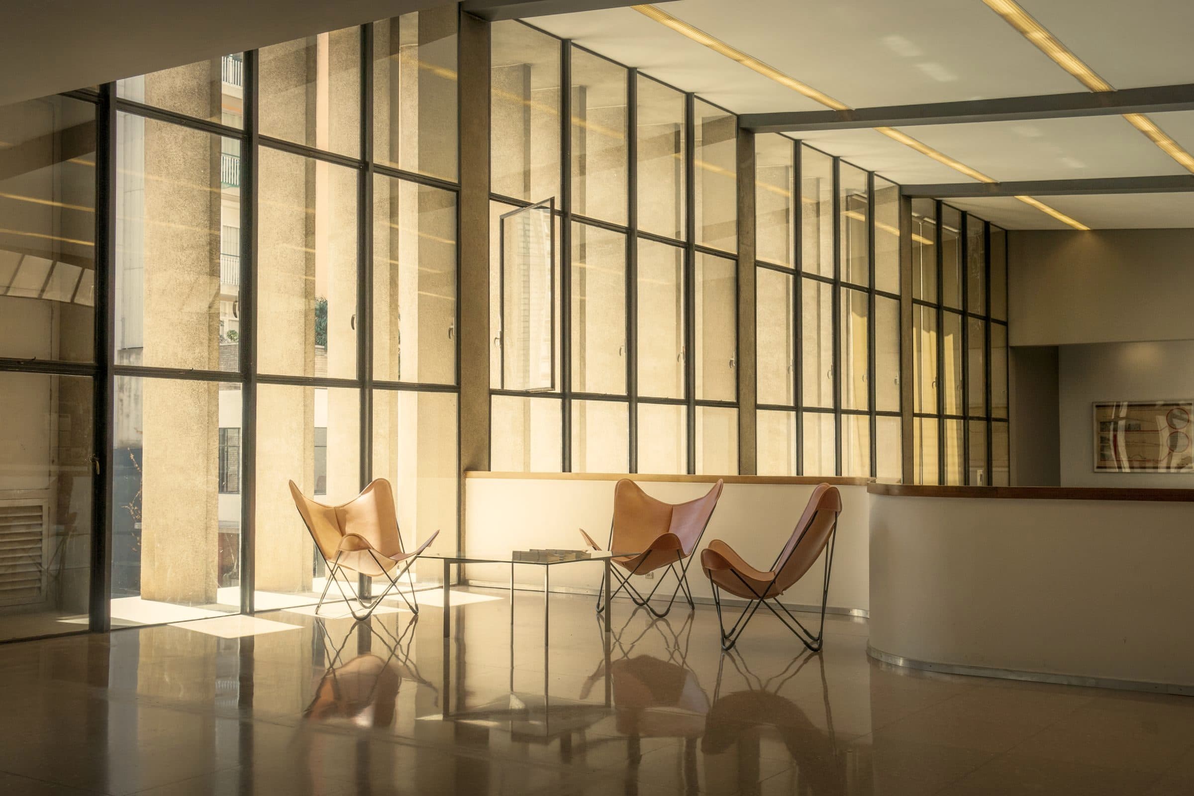 Sunlit modern commercial lobby behind a full-height glass entrance facade