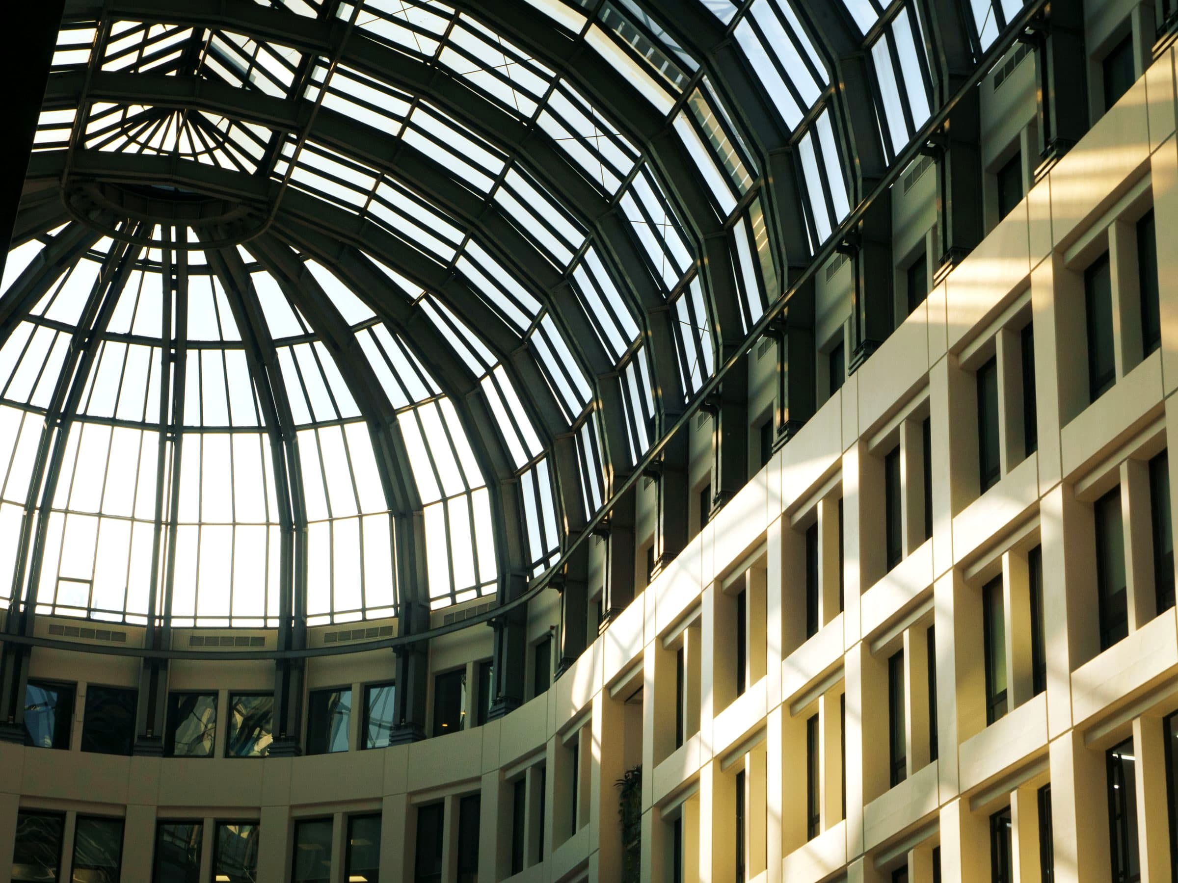 Sunlit glazed dome atrium over a modern commercial building against blue sky