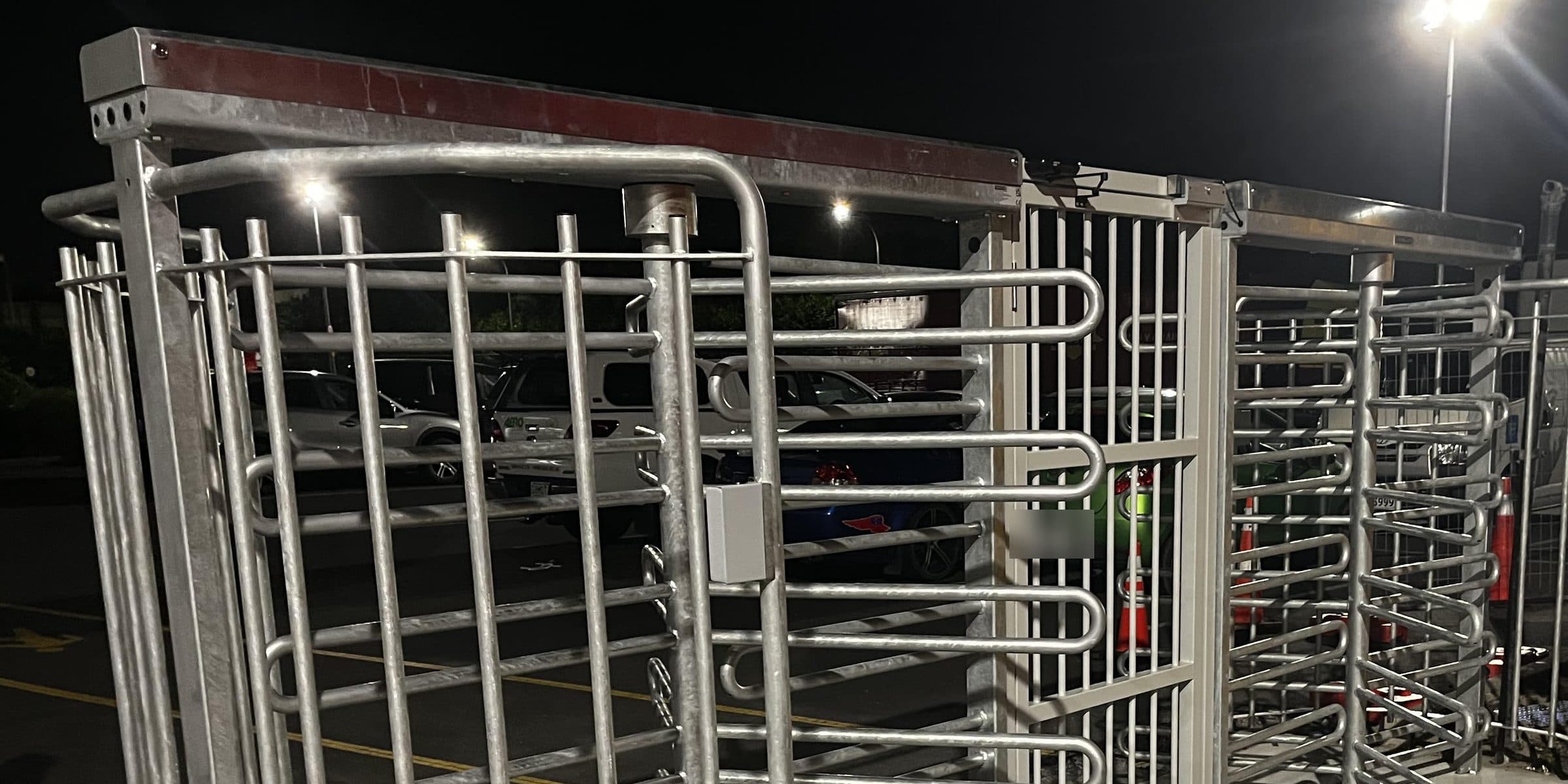 Hot dip galvanised full height turnstiles installed at a New Zealand site entrance at night, with a pedestrian gate alongside